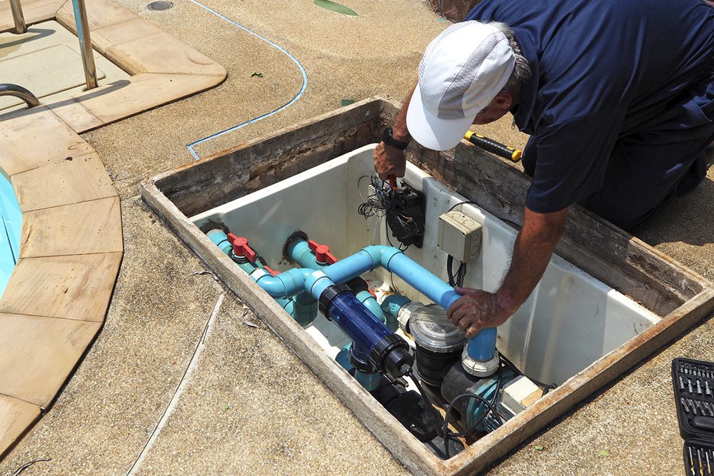 Technician repairing pool pump and piping